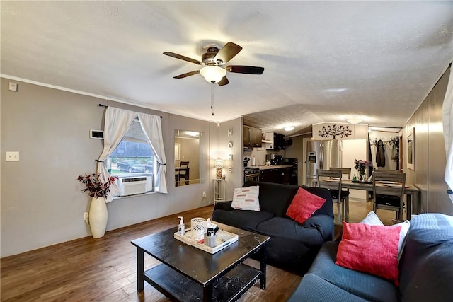 living area with cooling unit, wood finished floors, a ceiling fan, vaulted ceiling, and a textured ceiling