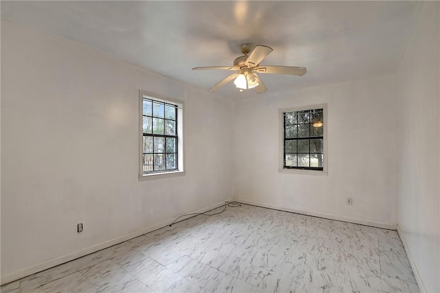 empty room with baseboards, marble finish floor, and a ceiling fan