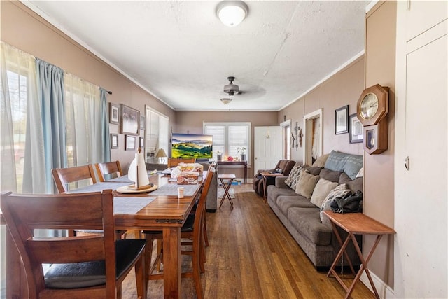 dining area with dark wood-type flooring, ornamental molding, and ceiling fan