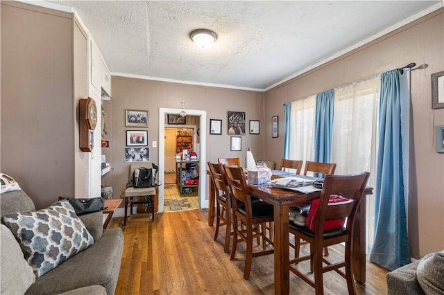 dining space with hardwood / wood-style flooring, ornamental molding, and a textured ceiling