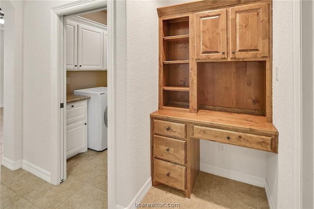 unfurnished office with washer / dryer, built in desk, and light tile patterned floors