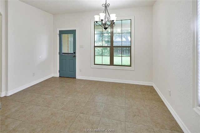 tiled empty room with a notable chandelier