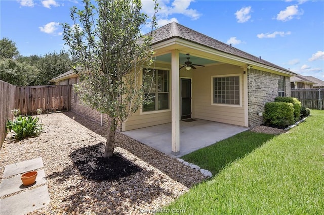 rear view of house featuring ceiling fan, a patio area, and a lawn