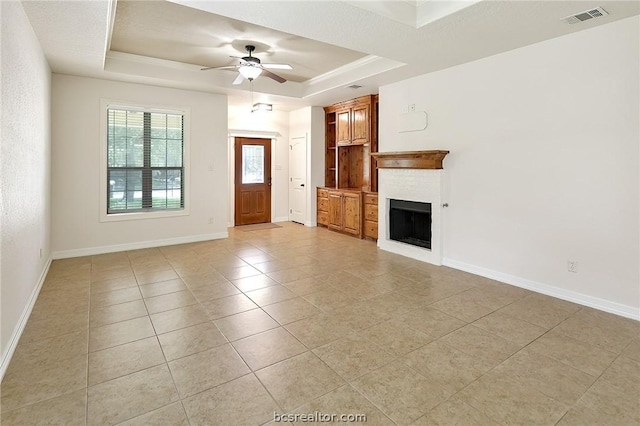 unfurnished living room with light tile patterned floors, a raised ceiling, and ceiling fan