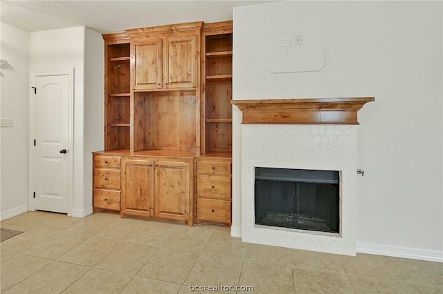 unfurnished living room featuring a textured ceiling, a brick fireplace, and light tile patterned flooring