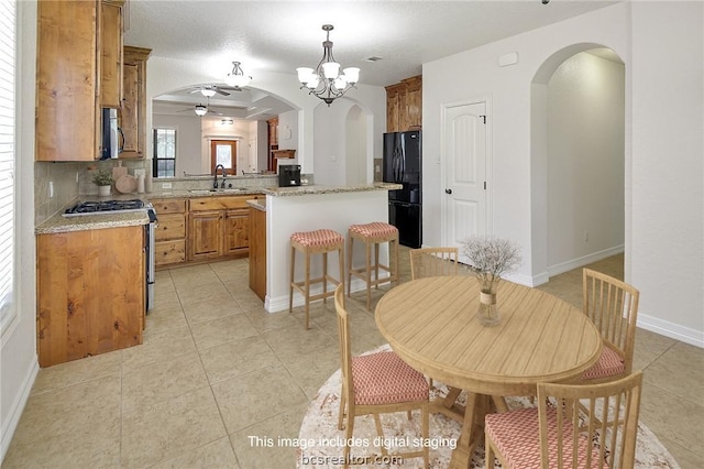 kitchen featuring a center island, sink, decorative backsplash, light stone countertops, and stainless steel appliances