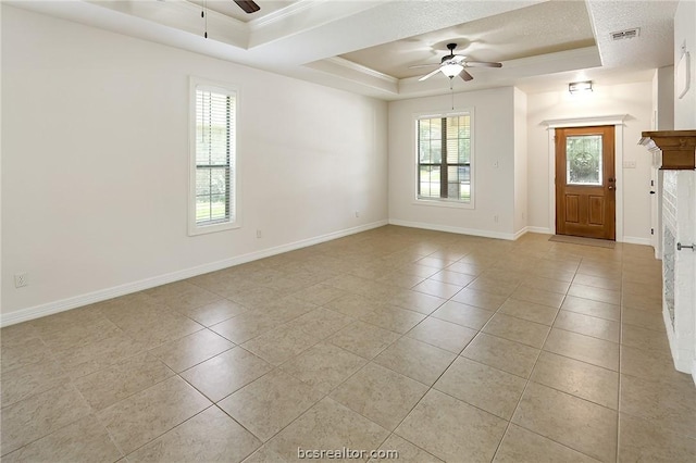 interior space with ceiling fan, a raised ceiling, crown molding, a textured ceiling, and a fireplace