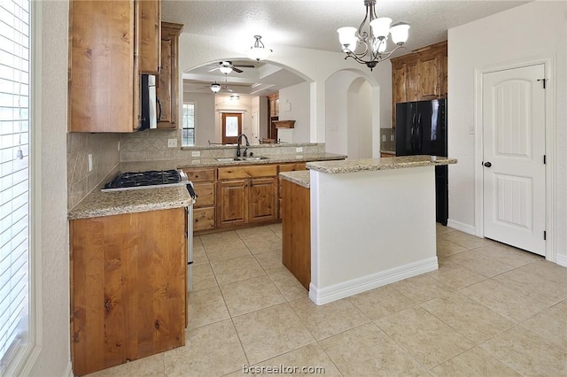 kitchen with a textured ceiling, backsplash, a kitchen island, and sink