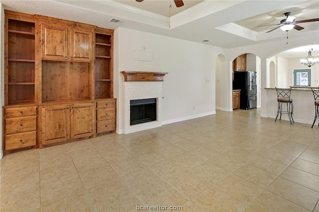 unfurnished living room with ceiling fan with notable chandelier, light tile patterned flooring, a raised ceiling, and crown molding