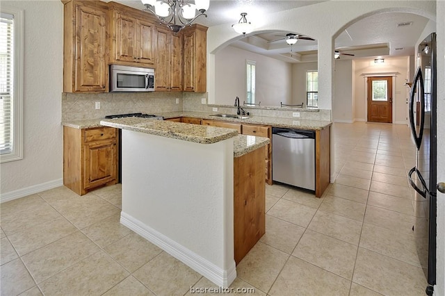 kitchen featuring a center island, sink, appliances with stainless steel finishes, tasteful backsplash, and light stone counters