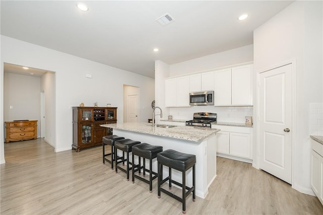 kitchen featuring an island with sink, appliances with stainless steel finishes, sink, and white cabinets