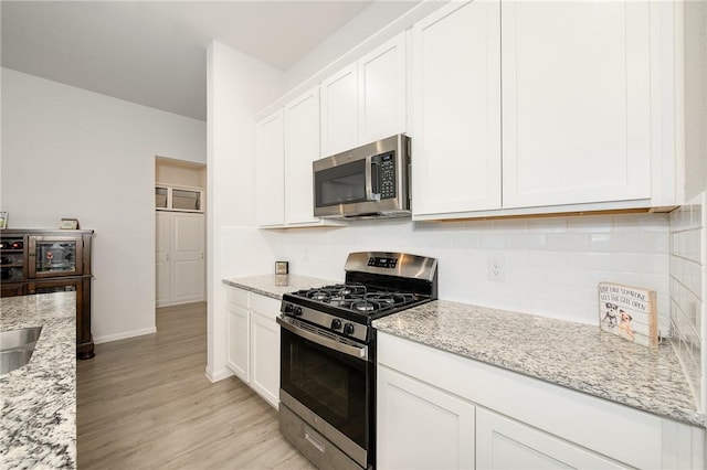 kitchen featuring stainless steel appliances, white cabinetry, and light stone countertops