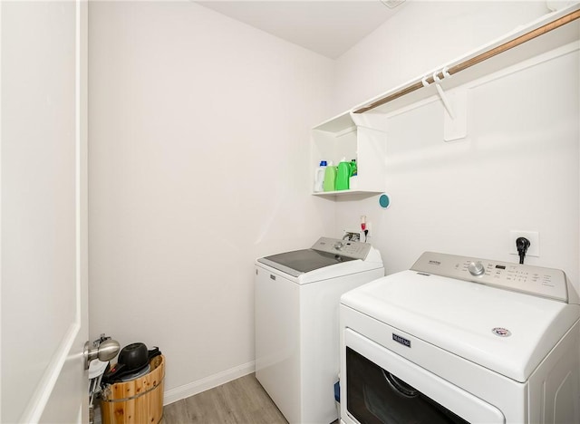 laundry room with washing machine and dryer and light hardwood / wood-style flooring