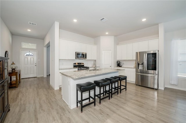 kitchen featuring white cabinetry, appliances with stainless steel finishes, sink, and an island with sink