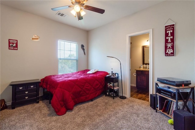 bedroom featuring connected bathroom, dark carpet, and ceiling fan