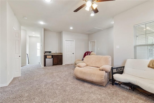 sitting room with ceiling fan and light colored carpet