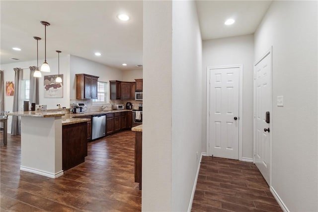 kitchen featuring pendant lighting, a breakfast bar, light stone counters, kitchen peninsula, and stainless steel appliances