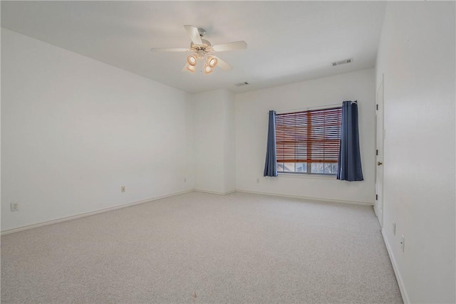 spare room featuring baseboards, visible vents, a ceiling fan, and light colored carpet