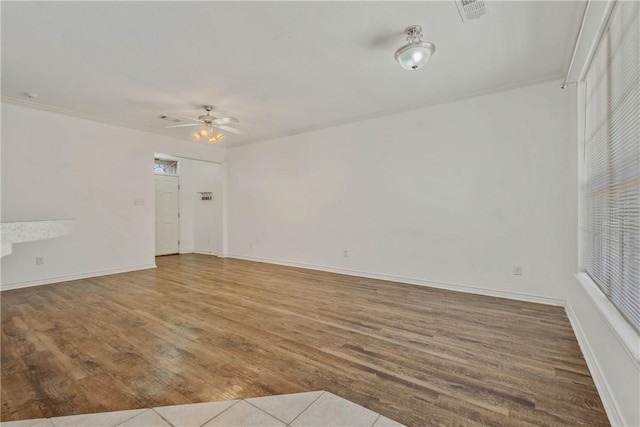 spare room with baseboards, visible vents, a ceiling fan, wood finished floors, and crown molding