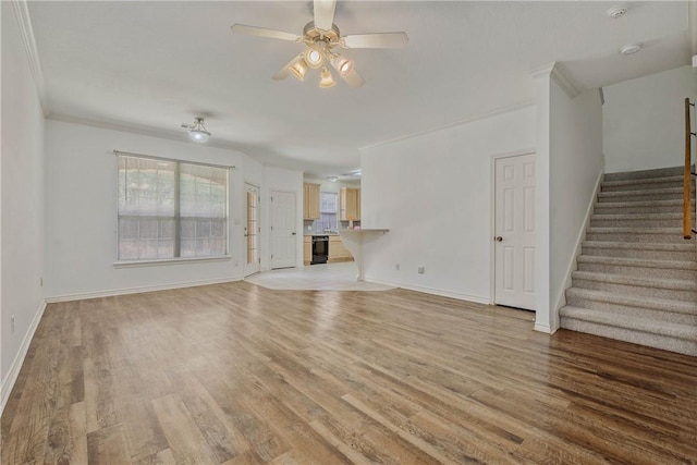 unfurnished living room featuring light wood finished floors, stairway, and a wealth of natural light