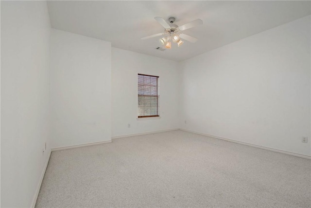 empty room with baseboards, a ceiling fan, and light colored carpet
