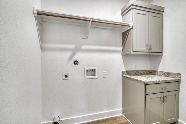 clothes washing area featuring washer hookup, dark wood finished floors, cabinet space, hookup for an electric dryer, and baseboards