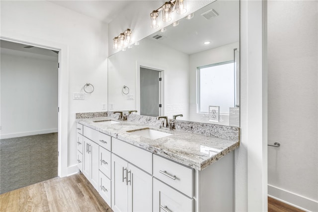 bathroom featuring wood finished floors, visible vents, a sink, and double vanity