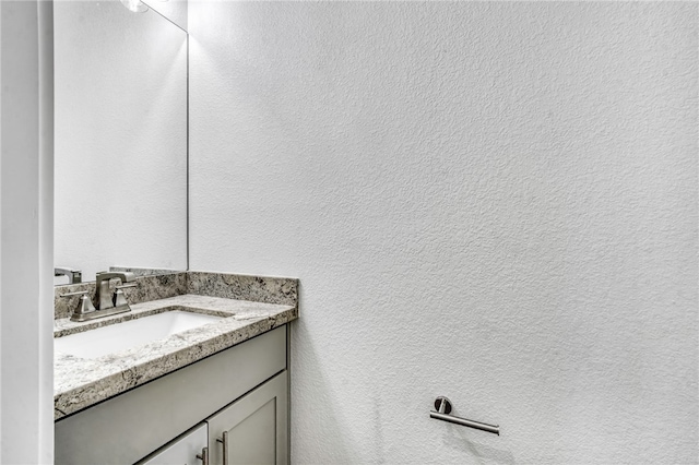 bathroom featuring a textured wall and vanity