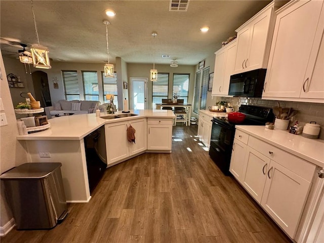 kitchen with sink, black appliances, decorative light fixtures, white cabinets, and dark hardwood / wood-style floors