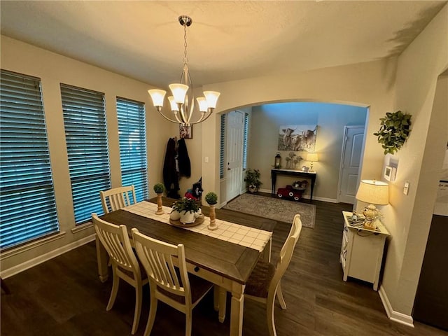 dining space with dark wood-type flooring and an inviting chandelier