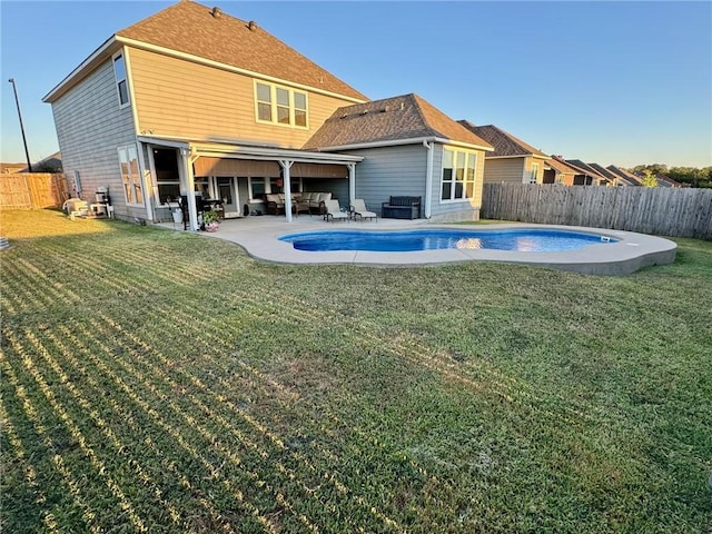 back of property with a lawn, a fenced in pool, an outdoor hangout area, and a patio