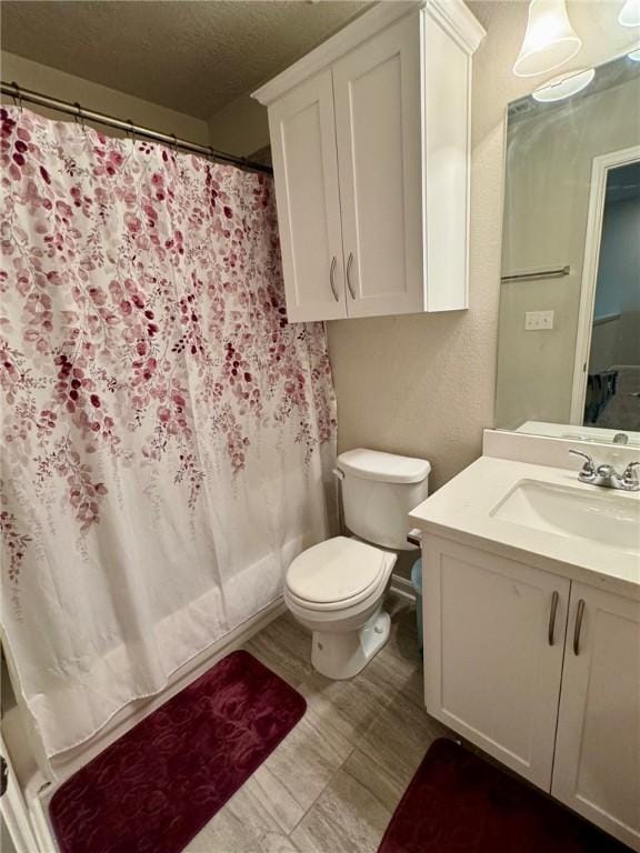 bathroom with a shower with curtain, vanity, toilet, and a textured ceiling