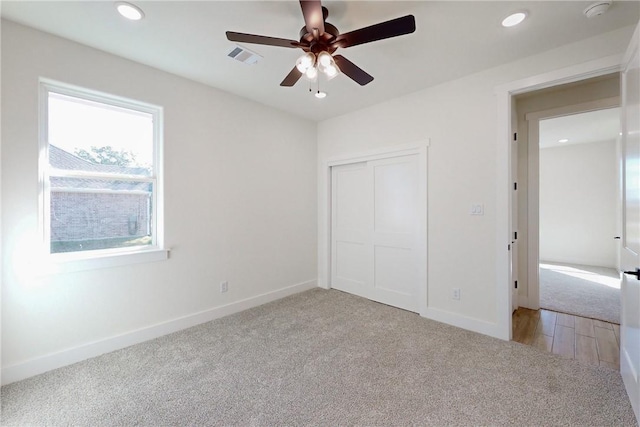 unfurnished bedroom featuring ceiling fan, light colored carpet, and a closet