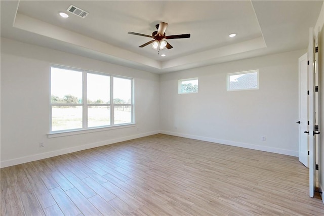 unfurnished room with a raised ceiling, light hardwood / wood-style flooring, and ceiling fan