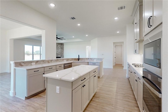 kitchen featuring a center island, sink, ceiling fan, appliances with stainless steel finishes, and kitchen peninsula