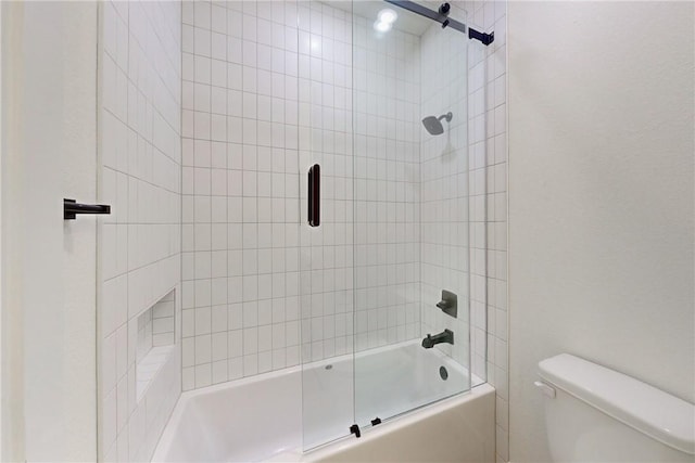 bathroom featuring combined bath / shower with glass door and toilet