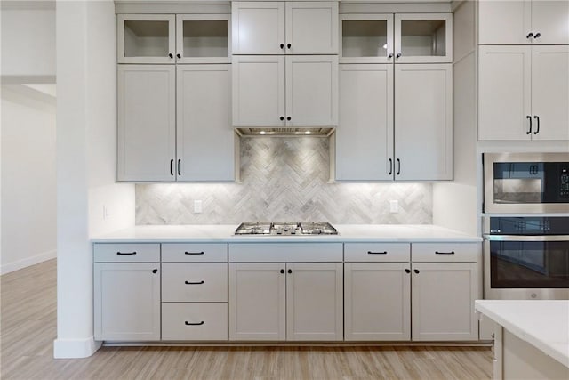 kitchen featuring white cabinetry, light wood-type flooring, stainless steel appliances, and tasteful backsplash