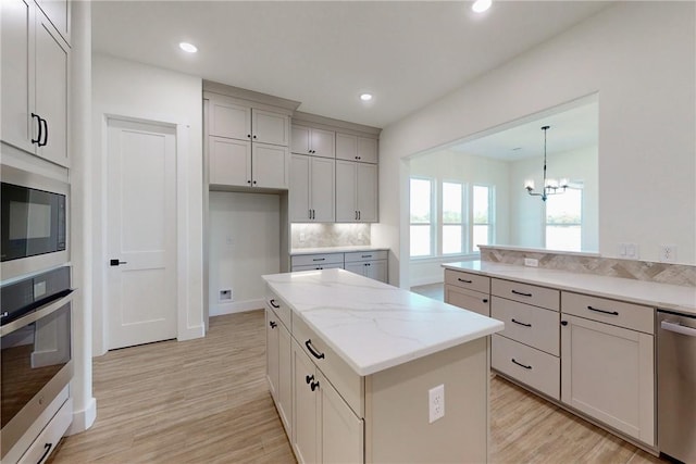 kitchen featuring appliances with stainless steel finishes, light wood-type flooring, a kitchen island, and hanging light fixtures