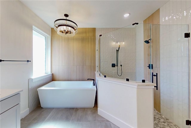 bathroom featuring shower with separate bathtub, vanity, an inviting chandelier, and tile walls