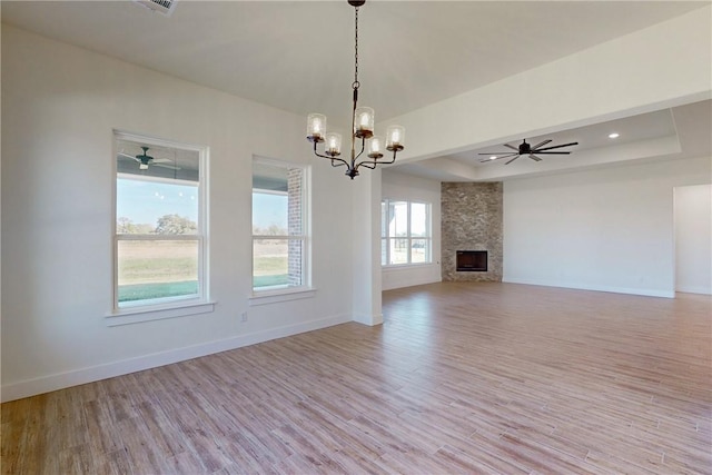 10120 Henley Cv, Iola, TX 77861 - unfurnished living room with a tray ceiling, light wood-type flooring, baseboards, a chandelier, and a ceiling fan