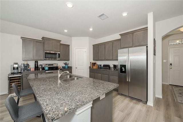 kitchen featuring visible vents, beverage cooler, arched walkways, stainless steel appliances, and a sink