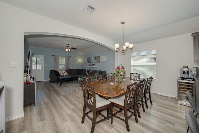 dining space featuring a healthy amount of sunlight, visible vents, light wood-style flooring, arched walkways, and wine cooler