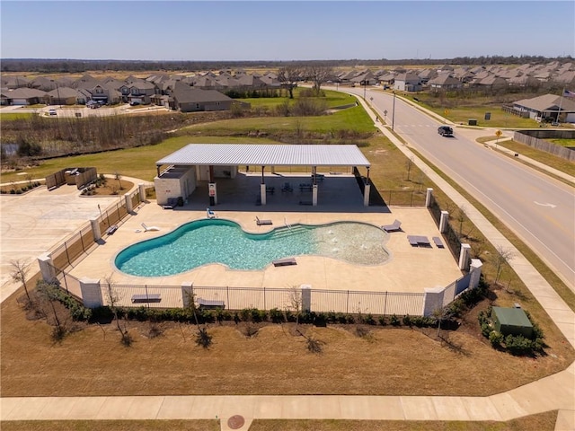 community pool with a residential view, fence, and a patio area