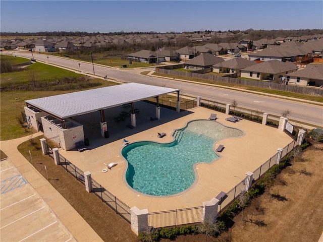 view of pool with a patio area, fence, and a residential view