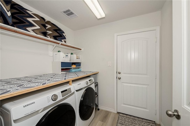 washroom featuring laundry area, visible vents, light wood finished floors, and washing machine and clothes dryer