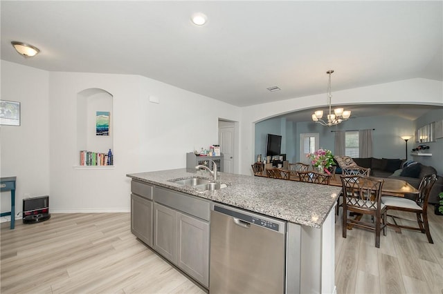 kitchen featuring light stone counters, light wood-style flooring, a sink, stainless steel dishwasher, and open floor plan