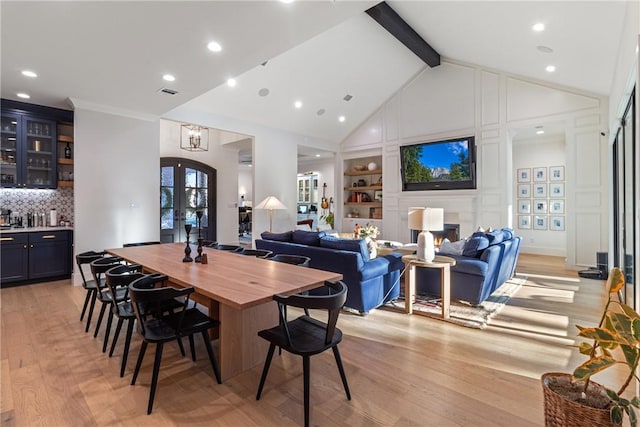 dining room with light wood-style flooring, beamed ceiling, french doors, high vaulted ceiling, and bar area