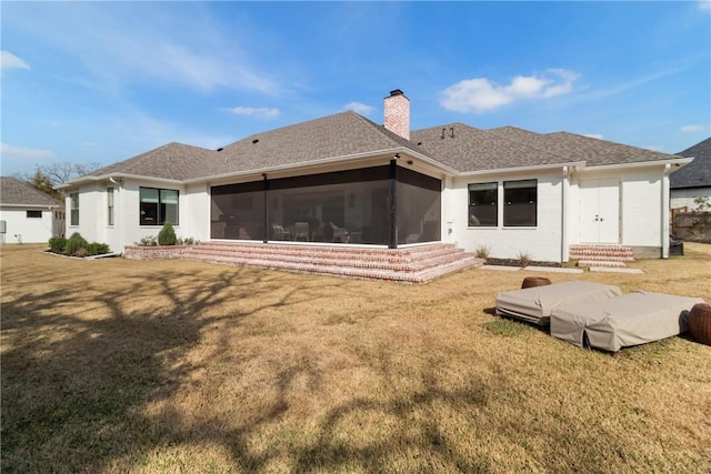 back of house with a sunroom, a shingled roof, a chimney, and a lawn