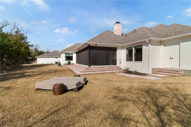 back of property featuring entry steps, a sunroom, a chimney, and a lawn