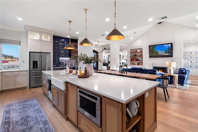 kitchen with pendant lighting, a spacious island, appliances with stainless steel finishes, open floor plan, and white cabinetry